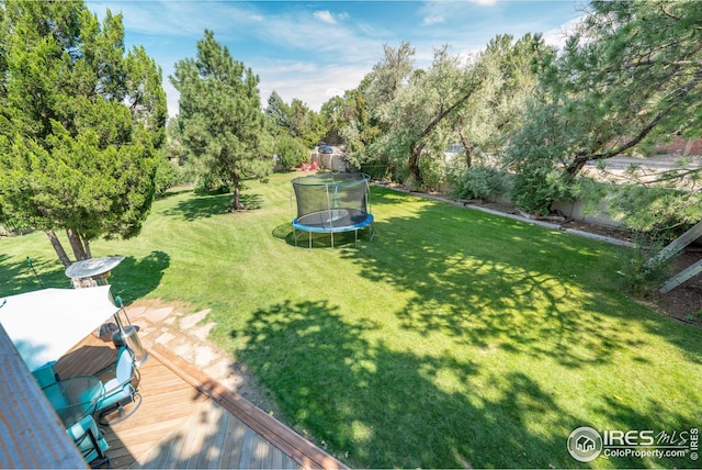 view of yard featuring a trampoline and a wooden deck