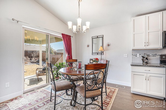 1115 Cottontail Ln, Wiggins, CO 80654 - dining space with baseboards, a chandelier, wood finished floors, and lofted ceiling