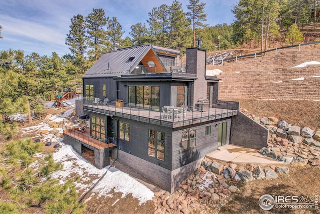 rear view of property with a chimney and a balcony