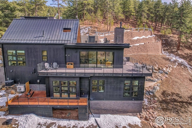 rear view of house featuring ac unit, metal roof, a balcony, and central AC