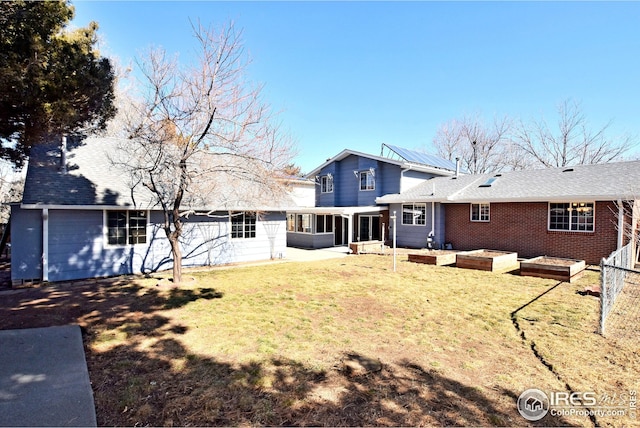 back of property with a garden, a yard, and a sunroom