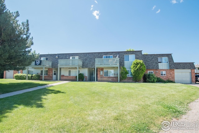 townhome / multi-family property with mansard roof, an attached garage, brick siding, roof with shingles, and a front lawn