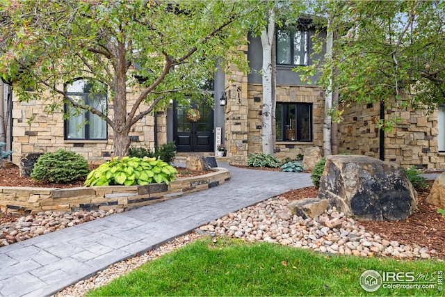 entrance to property featuring stone siding and french doors