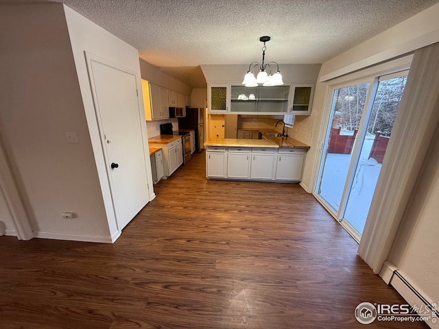 kitchen featuring dark wood-type flooring, an inviting chandelier, stainless steel appliances, a baseboard heating unit, and open shelves