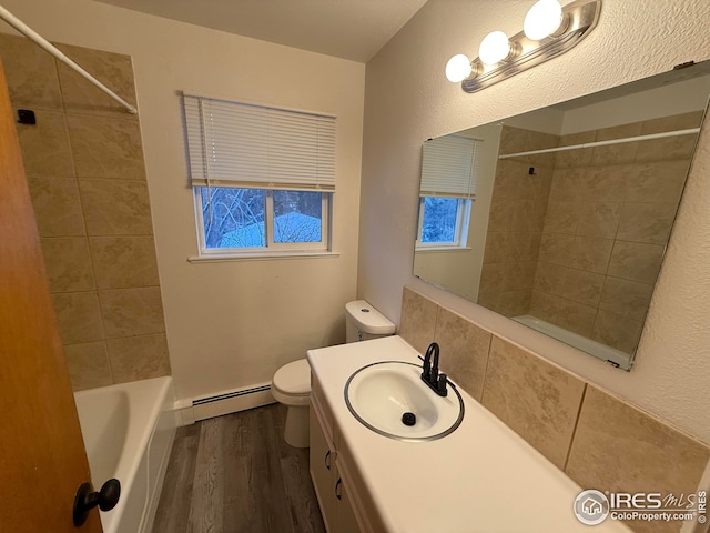 bathroom with toilet, a baseboard heating unit, wood finished floors, vanity, and shower / washtub combination