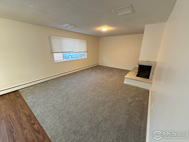 unfurnished living room featuring a premium fireplace, visible vents, dark colored carpet, and a textured ceiling