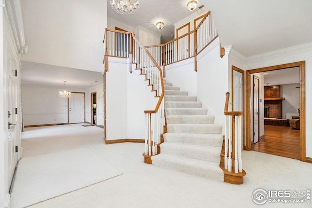 stairs featuring crown molding, carpet, baseboards, and an inviting chandelier