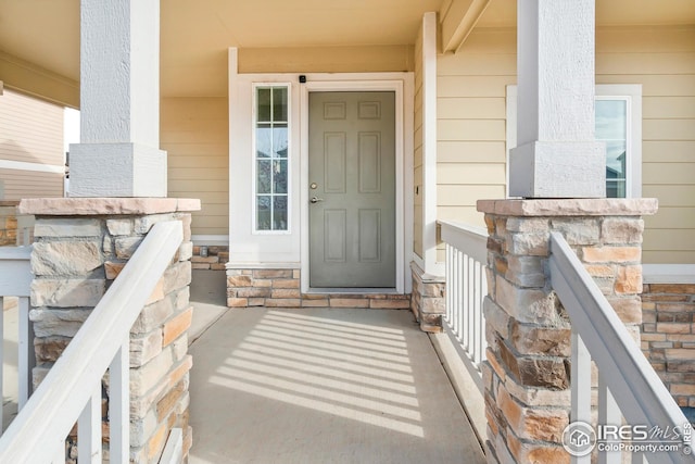 view of exterior entry with a porch and stone siding