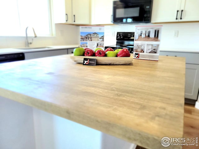 kitchen featuring a sink, light countertops, black appliances, and white cabinets