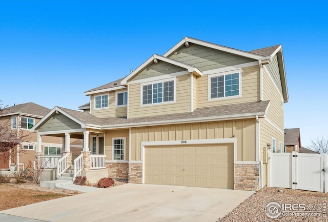 craftsman-style home with stone siding, covered porch, a garage, a gate, and driveway
