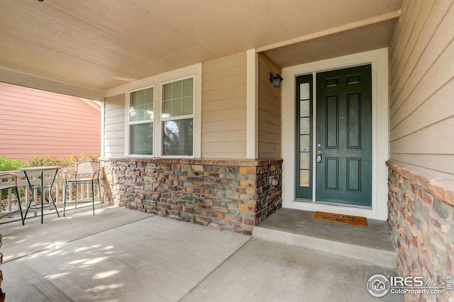 view of exterior entry with a porch and stone siding