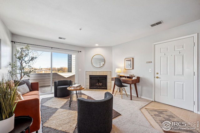 carpeted living room featuring a fireplace, visible vents, and baseboards