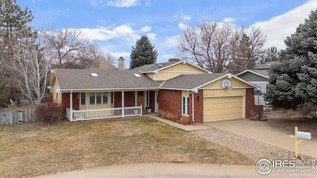 view of front of house with covered porch, brick siding, driveway, a chimney, and a front yard