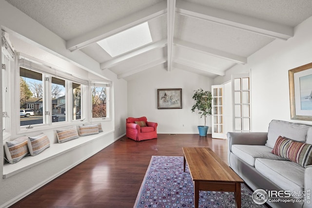 living room with vaulted ceiling with skylight, a textured ceiling, baseboards, and wood finished floors