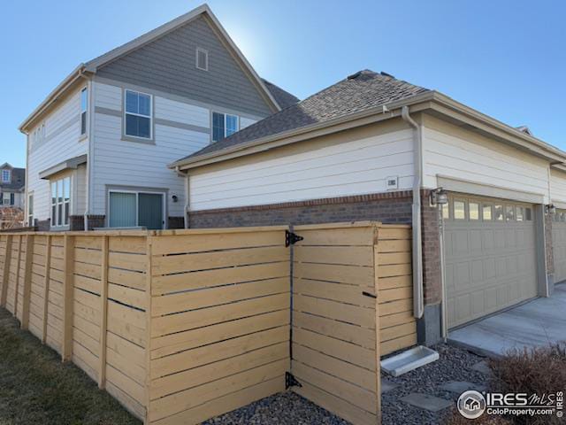 view of property exterior with brick siding, fence, and an attached garage