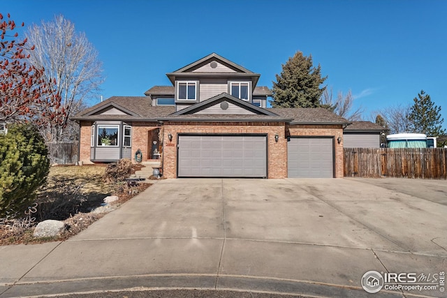 view of front of property with an attached garage, fence, concrete driveway, and brick siding