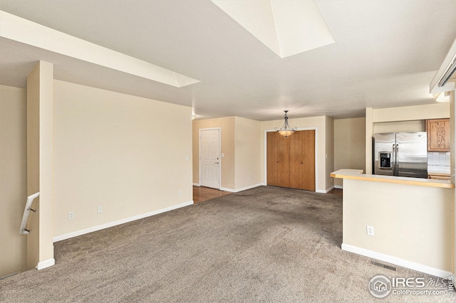 unfurnished living room featuring visible vents, baseboards, and dark colored carpet