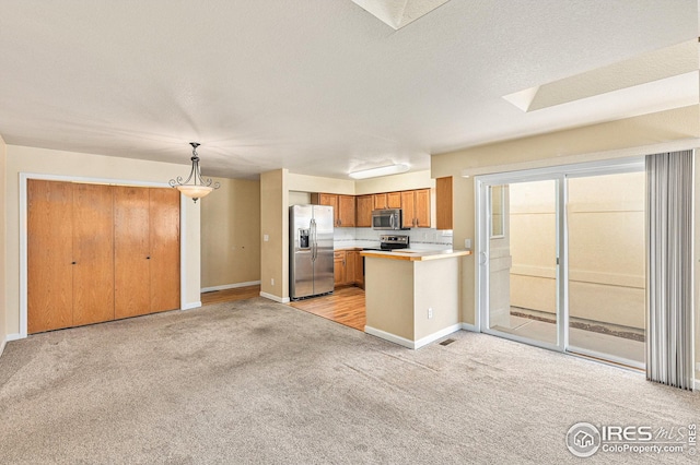 kitchen with open floor plan, stainless steel appliances, light countertops, and light colored carpet