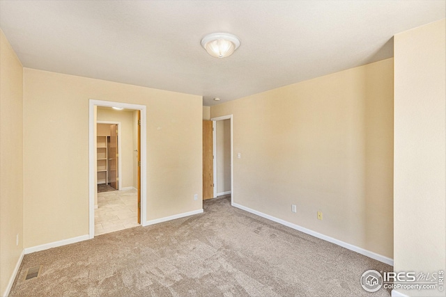 carpeted spare room with visible vents and baseboards