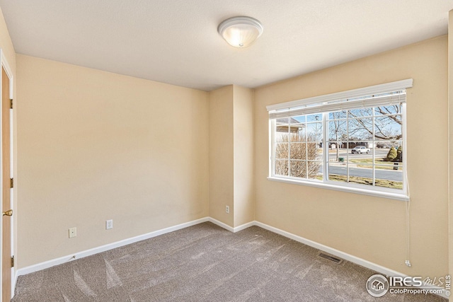 carpeted spare room featuring visible vents and baseboards