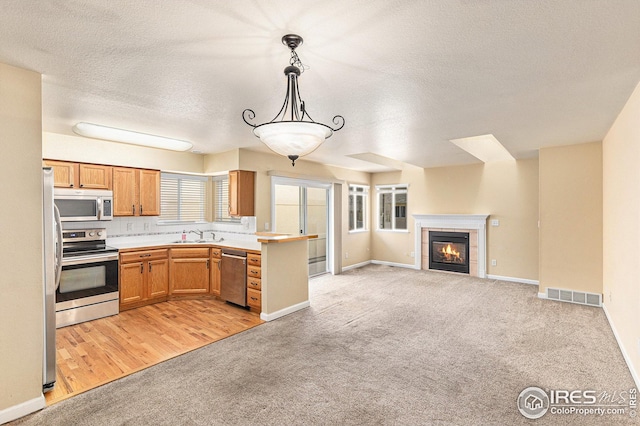 kitchen with visible vents, light colored carpet, appliances with stainless steel finishes, open floor plan, and light countertops