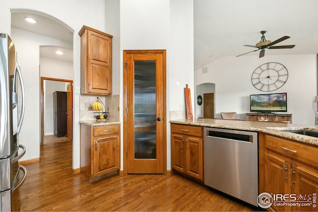 kitchen featuring brown cabinetry, a ceiling fan, appliances with stainless steel finishes, and wood finished floors