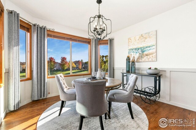 dining space featuring a notable chandelier, wainscoting, and wood finished floors