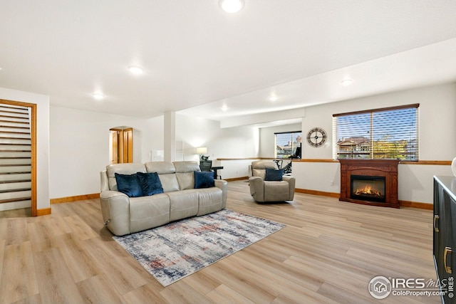 living area with baseboards, recessed lighting, light wood-style floors, and a glass covered fireplace