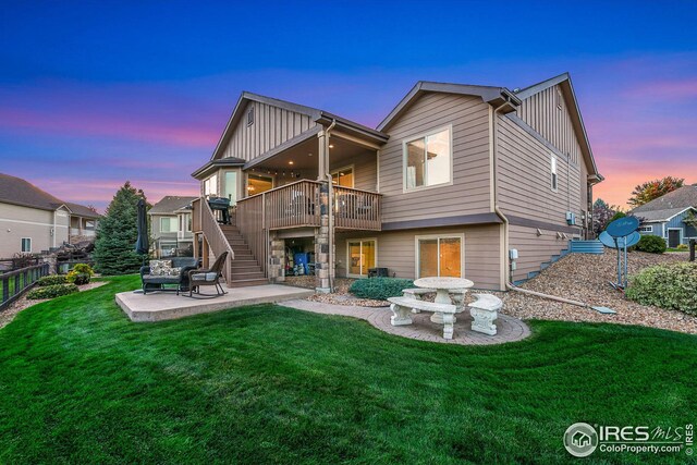 back of house with a lawn, stairs, board and batten siding, and a patio area