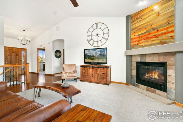 living area with a tile fireplace, baseboards, arched walkways, carpet floors, and ceiling fan with notable chandelier