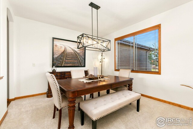 dining room with a chandelier, baseboards, and carpet floors