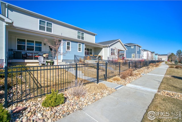 view of front of property featuring covered porch, fence private yard, and a residential view