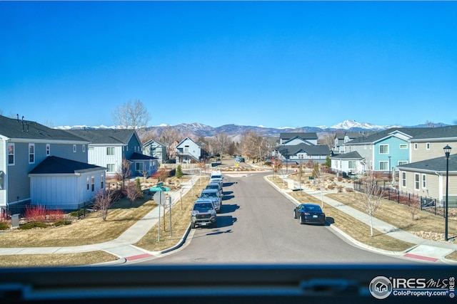 view of street featuring sidewalks, a residential view, a mountain view, and curbs