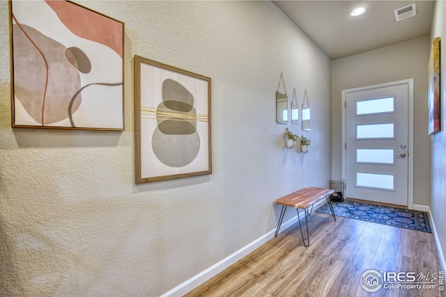 interior space with baseboards, visible vents, wood finished floors, and a textured wall