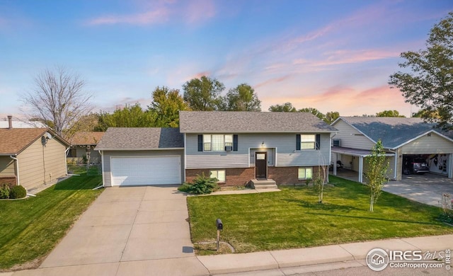 bi-level home featuring driveway, a front lawn, an attached garage, and brick siding