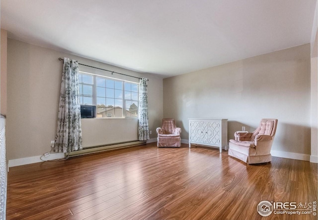 unfurnished room featuring baseboards, baseboard heating, and wood finished floors