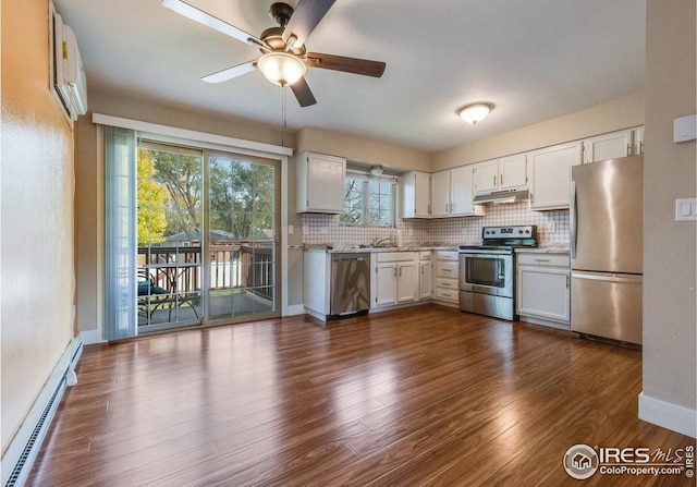 kitchen with tasteful backsplash, under cabinet range hood, a baseboard radiator, and stainless steel appliances