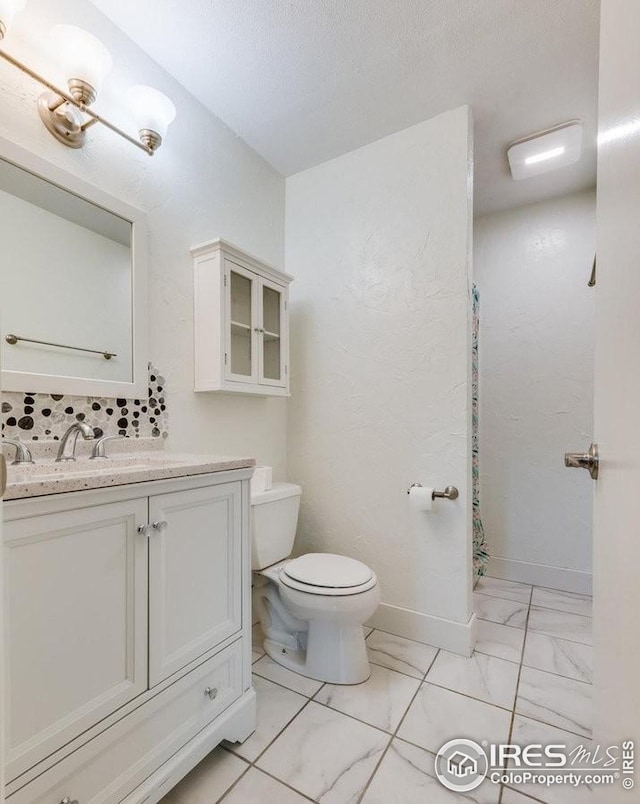 bathroom with marble finish floor, toilet, vanity, a textured ceiling, and baseboards