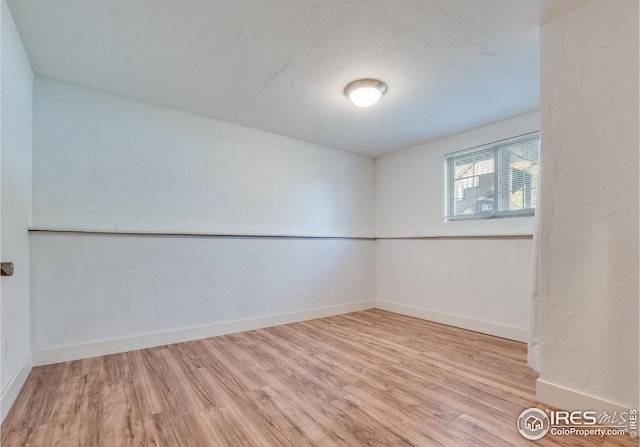 spare room featuring baseboards and wood finished floors