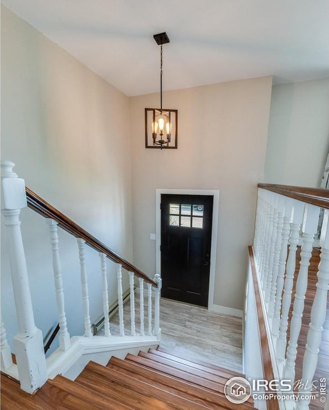 entrance foyer featuring stairs, baseboards, wood finished floors, and a notable chandelier