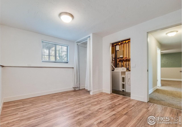 empty room featuring washing machine and dryer, light wood-style flooring, and baseboards