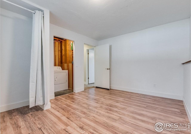 unfurnished bedroom with washer / clothes dryer, light wood-style flooring, and baseboards