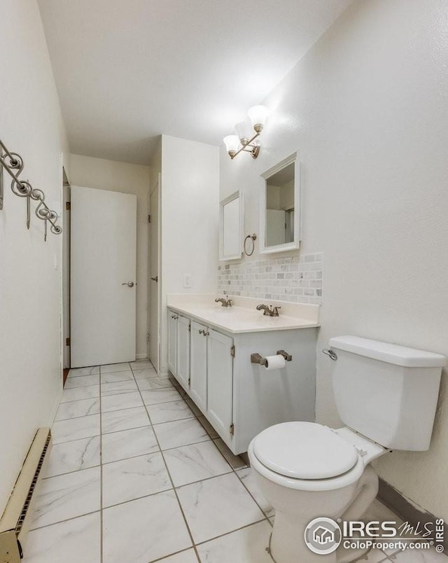 bathroom with toilet, vanity, marble finish floor, baseboard heating, and tasteful backsplash