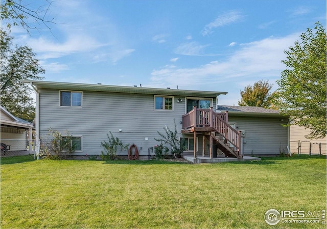 rear view of property featuring fence, stairway, and a lawn