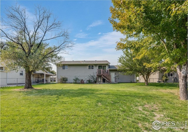 rear view of property featuring stairs, a yard, and fence