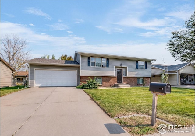 split foyer home featuring a garage, driveway, a front lawn, and brick siding