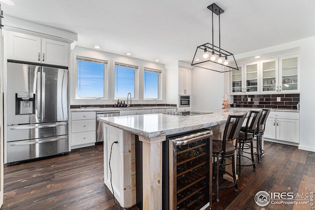 kitchen with beverage cooler, a sink, backsplash, a center island, and stainless steel appliances