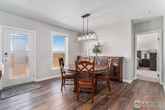 dining room featuring baseboards, visible vents, dark wood-style flooring, and a textured ceiling