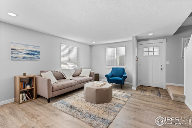 living room featuring a textured ceiling, baseboards, wood finished floors, and recessed lighting