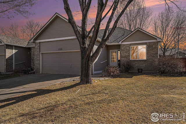 view of front of home featuring an attached garage, a front yard, concrete driveway, and brick siding